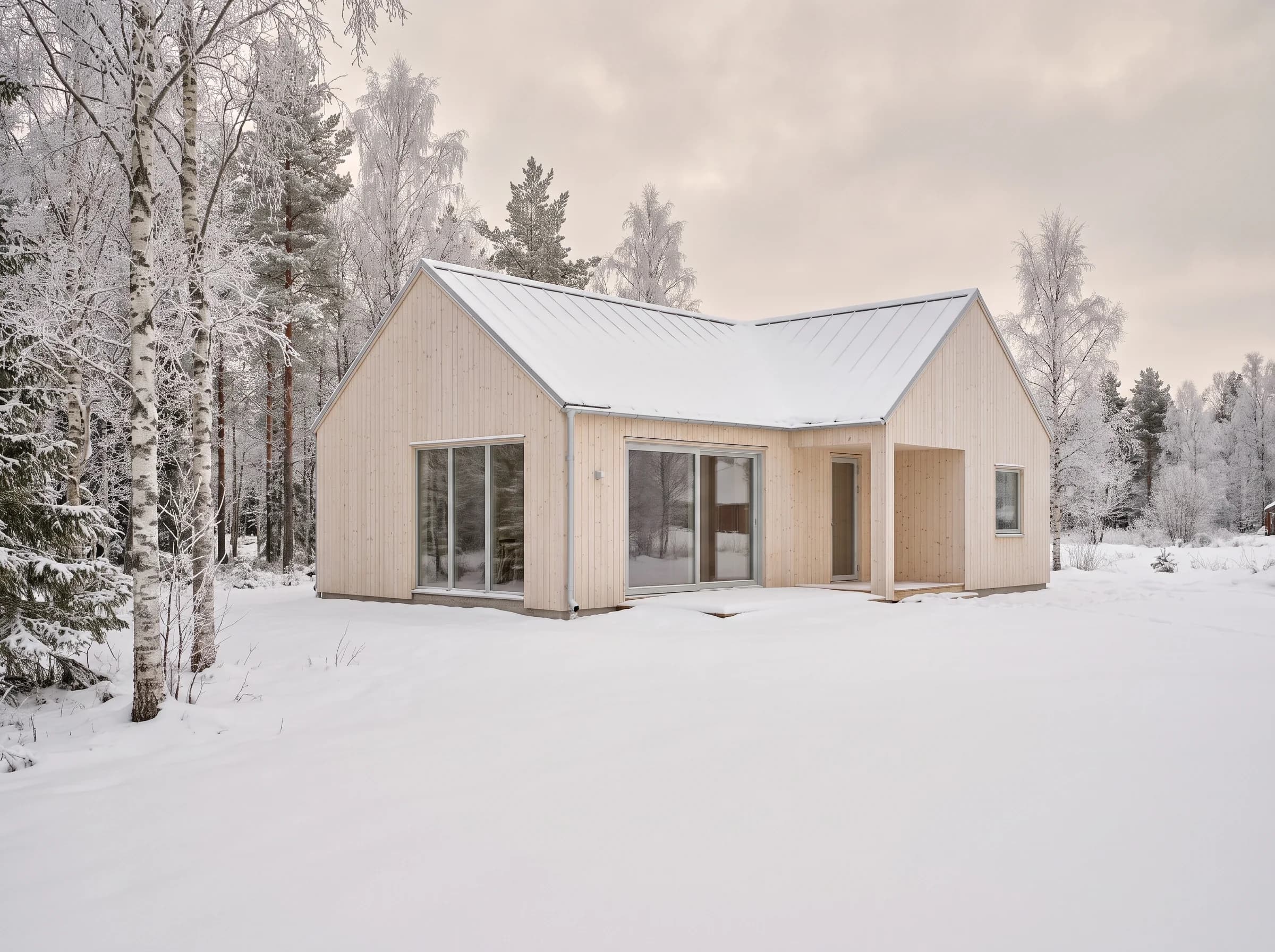 Nybyggt trähus i vinterlandskap med frostiga björkar